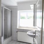 Badezimmer mit Dusche, Waschbecken und Fenster.