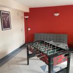 Fußballtisch mit grauem Sofa und roter Wand.