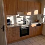 Küche mit Holzschränken, Herd, Spüle und Fenster