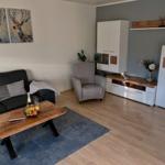 Wohnzimmer mit Sofa, Sessel, Couchtisch und Wandbildern