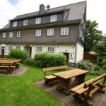 Haus mit Garten und Holztischen für Gäste