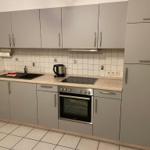 Küche mit grauen Schränken, Herd und Spüle.