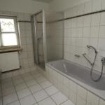 Badezimmer mit Badewanne, Dusche und Fenster.