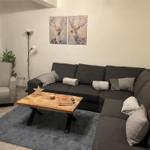 Wohnzimmer mit Ecksofa, Holztisch und Wandbildern mit Hirschen.