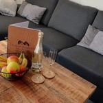 Holztisch mit Obstschale, Champagner und Kissen auf Sofa