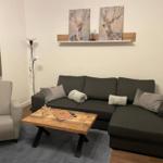 Ein Wohnzimmer mit grauem Sofa, Holztisch und Wandbildern von Hirschen.