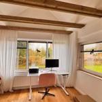 Zimmer mit Schreibtisch, Bett und Holzbalken an der Decke.