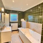 Badezimmer mit Badewanne, Waschbecken und grünen Fliesen