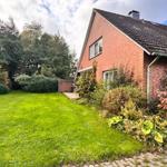 Rotes Backsteingebäude mit Garten und Blumenbeet. 