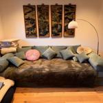 Großer Sofa mit Kissen und Wandbildern im Wohnzimmer.