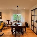 Wohn- und Essbereich mit Holzboden, Sofa, Tisch und Schiebetüren.