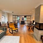 Wohnzimmer mit Sofa, gelber Sessel und Kamin. Essbereich und Schlafzimmer im Hintergrund.