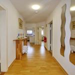 Flur mit Holzboden, Spiegel und Tisch mit Vasen.