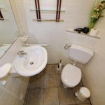 Badezimmer mit Waschbecken, Toilette und Spiegel.