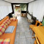 Wohn- und Essbereich mit Sofa, Tisch und TV. Blick auf den Außenbereich.