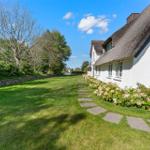 Wohnhaus mit Strohdach und gepflegtem Garten mit Stegweg.