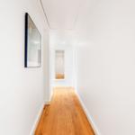 Flur mit Holzboden und Wandbild. Türen und Wände sind weiß.