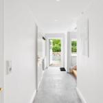 Hallen mit weißen Wänden, grauem Boden und Tür zum Garten.