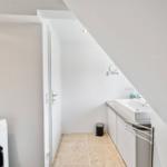 Waschmaschine, Waschbecken und Spiegel unter Dachschrägen