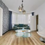 Wohnzimmer mit Sofa, Glas-Tisch und moderner Sitzgelegenheit. Blick auf angrenzende Räume.