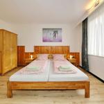 Schlafzimmer mit Doppelbett, Holzmöbel und Fenster mit Vorhängen.