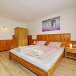 Schlafzimmer mit Holzbett, Nachttischen und Kleiderschrank. Wandbild und Holzvertäfelung.