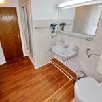 Badezimmer mit Dusche, Waschbecken, Toilette und Haartrockner.