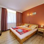 Schlafzimmer mit Doppelbett, Holzboden und orange Wand.