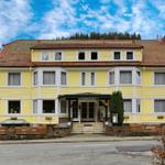Gelbes Haus mit rotem Dach und Fenstern. Eingang mit Säulen und Treppe.