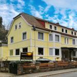 Gelbes Haus mit Satteldach und Balkon. Schild: Pension Haus Sonneck.