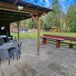 Terrasse mit Tischen, Stühlen und Holzbank im Garten.