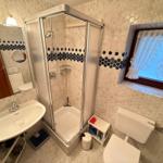 Badezimmer mit Dusche, Waschbecken und WC. Wand- und Bodenfliesen mit Mosaikverzierung.