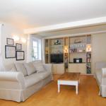 Wohnzimmer mit zwei Sofas, Holzboden und eingebautem Bücherregal mit Fernseher.