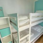 Zimmer mit Doppelstockbett und weißen Matratzen. An der Wand hängt ein Bild.