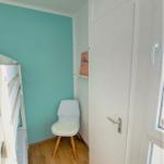 Zimmer mit Doppelstockbett, Stuhl und Tür. Wandfarbe Türkis.