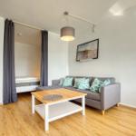 Wohnzimmer mit Sofa, Tisch und Bett im Hintergrund.