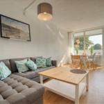 Wohnzimmer mit Sofa, Tisch und Blick auf Balkon