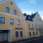 Gelbes Gebäude mit Fenstern und Schildern wie Getränke-Markt und Fremdenzimmer.