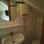 Badezimmer mit Waschbecken, Spiegel und Heizung.