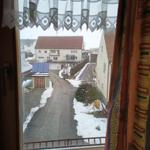 Aus dem Fenster blickt man auf eine schneebedeckte Straße mit Häusern.
