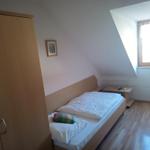 Schlafzimmer mit Dachschrägen, Bett, Kleiderschrank und Fenster.