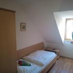 Schlafzimmer mit Dachschrägen, Bett, Kleiderschrank und Fernseher.