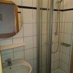 Bad mit Dusche, Waschbecken und runden Spiegel