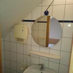 Badezimmer mit Waschbecken, Spiegel und Heizung an geneigter Wand