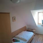 Schlafzimmer mit Dachschrägen, Bett, Kleiderschrank und Fenster.