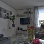 Wohnzimmer mit Fernseher, Sitzgelegenheit und Fenster