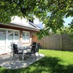 Hinterhof mit Sitzgruppe unter Bäumen und grünem Rasen.