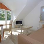 Wohnzimmer mit Sofa, Tisch und Fernseher unter Dachschrägen.