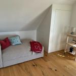 Ein Schlafzimmer mit Sofa, Kleiderschrank und Holzboden.