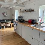 Küche mit Holzwerkstoffe und Edelstahlspüle. Essbereich mit runden Tisch und Stühlen.